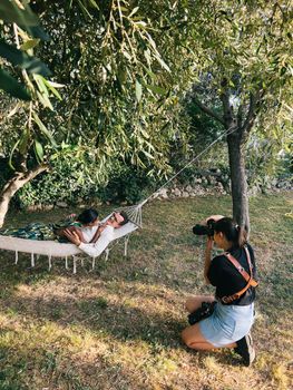 Girl photographer photographs a woman lying on a man in a hammock. High quality photo