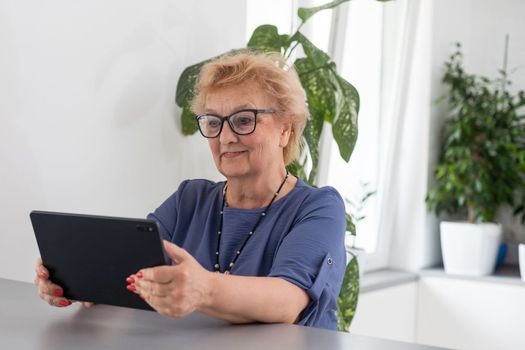 telemedicine concept, old woman with tablet pc during an online consultation with her doctor in her living room.