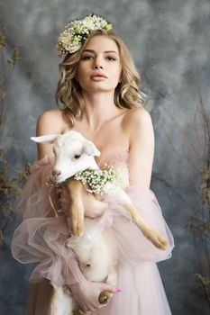 A young blonde woman in an airy pink dress with a white kid. Spring portrait of a woman