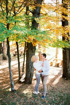 Man and woman stand hugging in the autumn forest under a tree. High quality photo