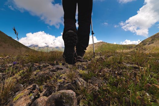 Close-up of boots while hiking on a trail in the mountains. Man walking in sports shoes overlooking nature from the ground.