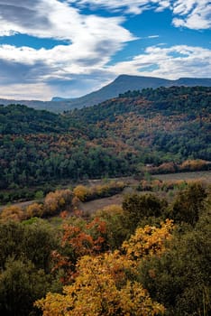 View of the mountains and hills in the Var department in France, in late fall. The leaves of the trees are turning yellow and red