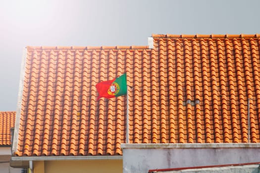 portuguese flag on a tiled roof background , summer evening