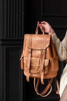 photo of a light brown leather backpack with antique and retro look. indoors photo.