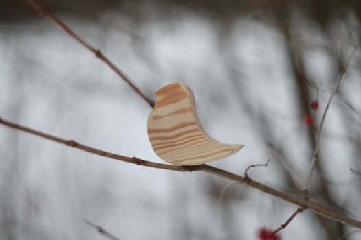 Wooden handmade toy bird on the tree branch on a winter day. Hello Spring concept. Winter landscape