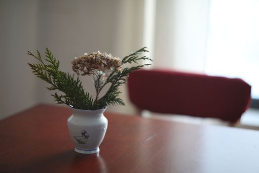 Soft home decor, white jug, vase with flowers on a dark vintage table background. Cozy Interior details.