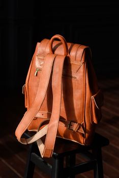 photo of a orange leather backpack with antique and retro look. indoors photo.