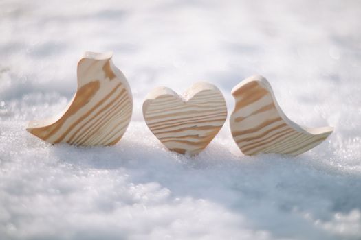 Beautiful decorative small wooden toy birds on white snow in winter. Easter, Spring decoration. Handmade wooden toys.