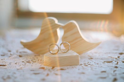 Two wooden handmade toy birds with two gold wedding rings and heart. Wedding, love, proposal, marriage, family concept.