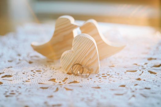 Two wooden handmade toy birds with two gold wedding rings and heart. Wedding, love, proposal, marriage, family concept.