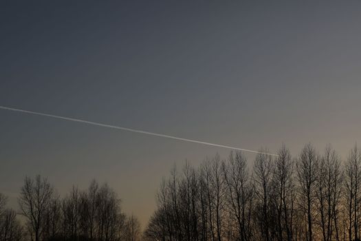airplane flies in sunset sky and leaving trail. Amazing panoramic sunrise or sunset sky. Gradient color. Sky texture, abstract nature background