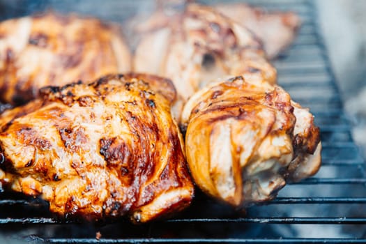 Chicken thighs Barbecue on The Hot Grill Close-up. Fire flames in the background