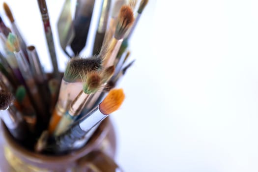 Artist's workplace. Different size and quality artistic brushes in ceramic jug.