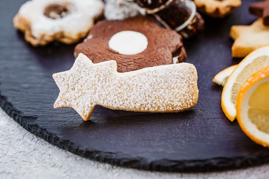 Tasty homemade Christmas cookies on black plate, closeup view