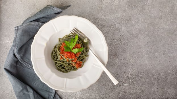 Healthy clean eating food: spirulina spaghetti with red caviar on concrete background with copy space, top view. Asian food creative concept