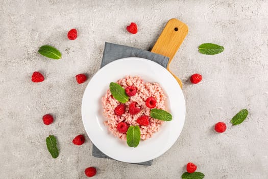 Healthy food on gray concrete background. Fresh raspberries risotto on a delicate and elegant dish