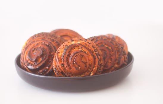 Sweet homemade cinnamon buns on a black ceramic plate.