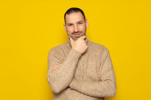 Problem solution. Bearded Hispanic man in a beige turtleneck gets rid of a problem, and. he looks up, makes up an idea. isolated yellow background