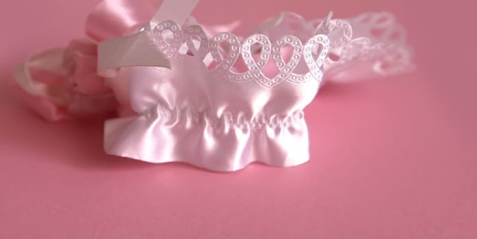 The bride's garter on a pink background. Wedding dress detail.