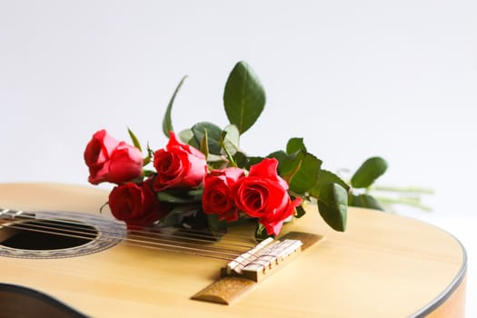 Classic guitar and red roses on white background.