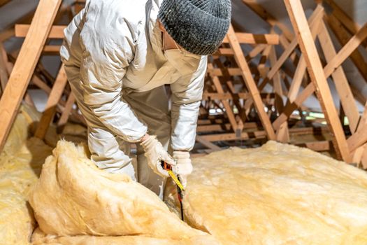 cutting glass wool when insulating the ceiling on the roof.