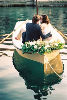 Man and woman hug and almost kiss in a boat decorated with flowers. High quality photo