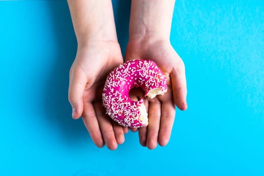 Hand holding half eaten sweet pink donut isolated. Half eaten donut isolated.