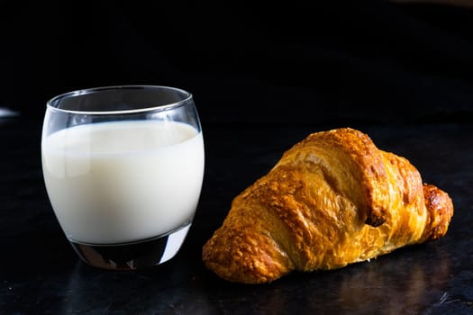 Fresh white bread and milk in white glass on black stone table background. Top view Studio shot