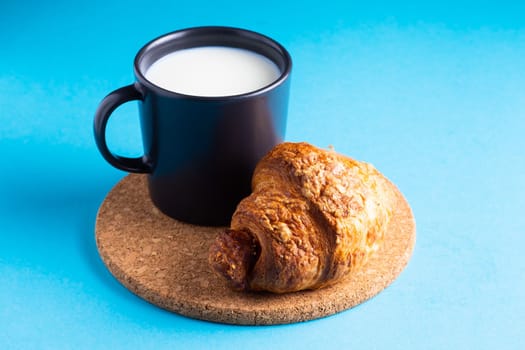 Breakfast bread and cup of milk on yellow and blue background