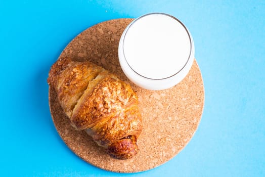 Breakfast bread and cup of milk on yellow and blue background