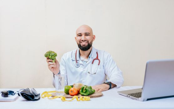 Portrait of smiling nutritionist holding a broccoli. Smiling nutritionist doctor at his desk holding a broccoli