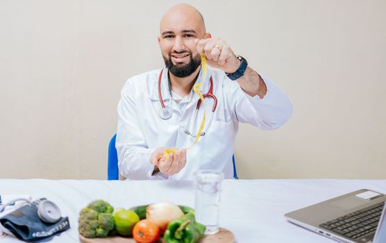 Nutritionist at his desk holding a tape measure. Young doctor nutritionist at her desk holding measuring tape. Diet and nutrition concept