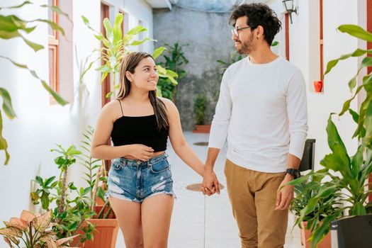 Smiling happy couple walking in hotel corridor. Young couple walking in corridor of tropical hotel