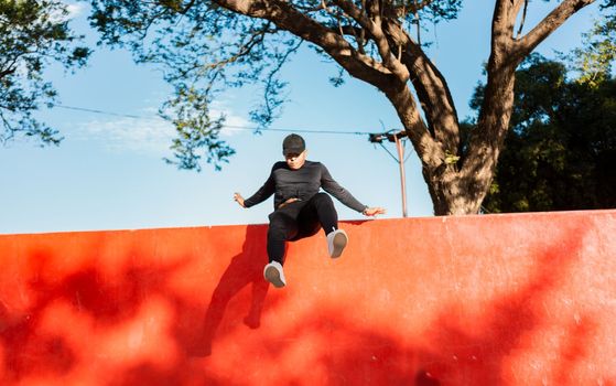 Young man doing jumping parkour at sunset. Guy doing wall jump parkour, Artistic image of man doing parkour