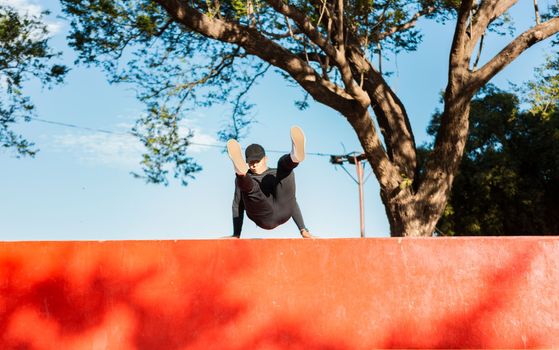 Guy doing wall jump parkour. Young man doing jumping parkour at sunset. Artistic image of man doing parkour