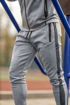 Athletic faceless man in a gray suit stands on the sports ground
