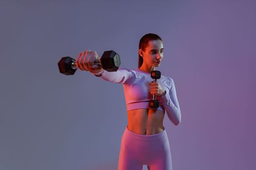 Woman doing exercises with dumbbells on studio background . Sport and healthy lifestyle