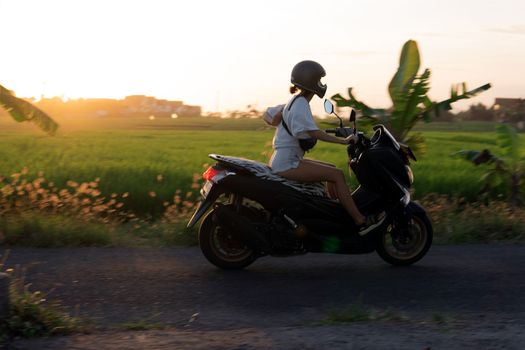 young girl on a motor scooter. bali