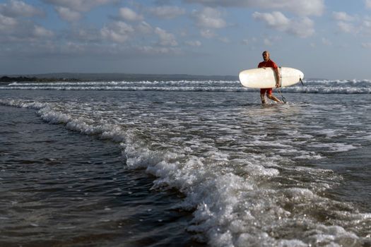 surfer walking along the beach. bali