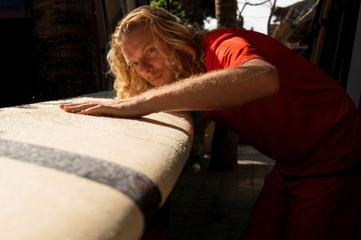 he surfer washes his board with water. bali