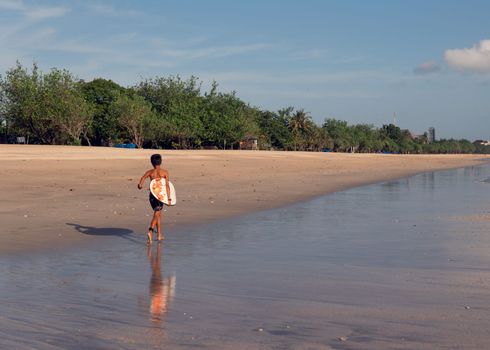 surfer walking along the beach. bali