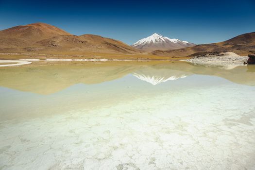 Salt lake reflection and idyllic volcanic landscape at sunrise, Atacama desert, Chile border with Bolivia