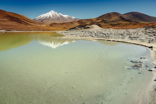 Salt lake reflection and idyllic volcanic landscape at sunrise, Atacama desert, Chile border with Bolivia