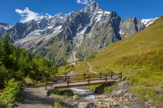 Idyllic alpine landscape of Aosta valley near Mont Blanc massif with river and bridge, Italy