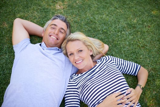 Romance inspired by natures beauty. High angle portrait of a mature couple lying in the park