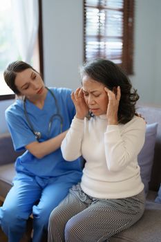 Portrait of a female doctor talking to an elderly patient showing headache