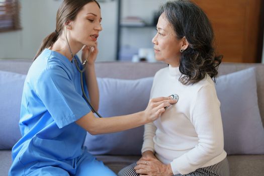 Portrait of a female doctor using a stethoscope to check the pulse of an elderly patient