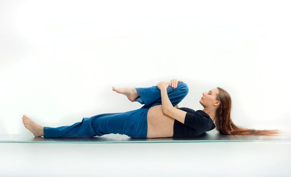 Pleasant pregnant woman posing in profile and trying yoga Young happy expectant relaxing, thinking about her baby and enjoying her future life. Motherhood, pregnancy, yoga concept.