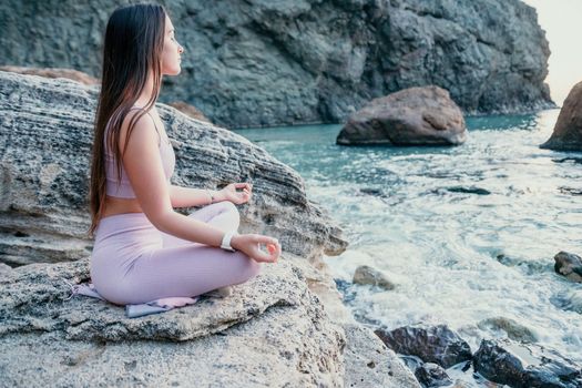 Young woman with black hair, fitness instructor in pink sports leggings and tops, doing pilates on yoga mat with magic pilates ring by the sea on the beach. Female fitness daily yoga concept