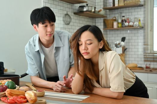 Upset young woman during quarreling with her husband in kitchen. Married problems and conflicts concept.